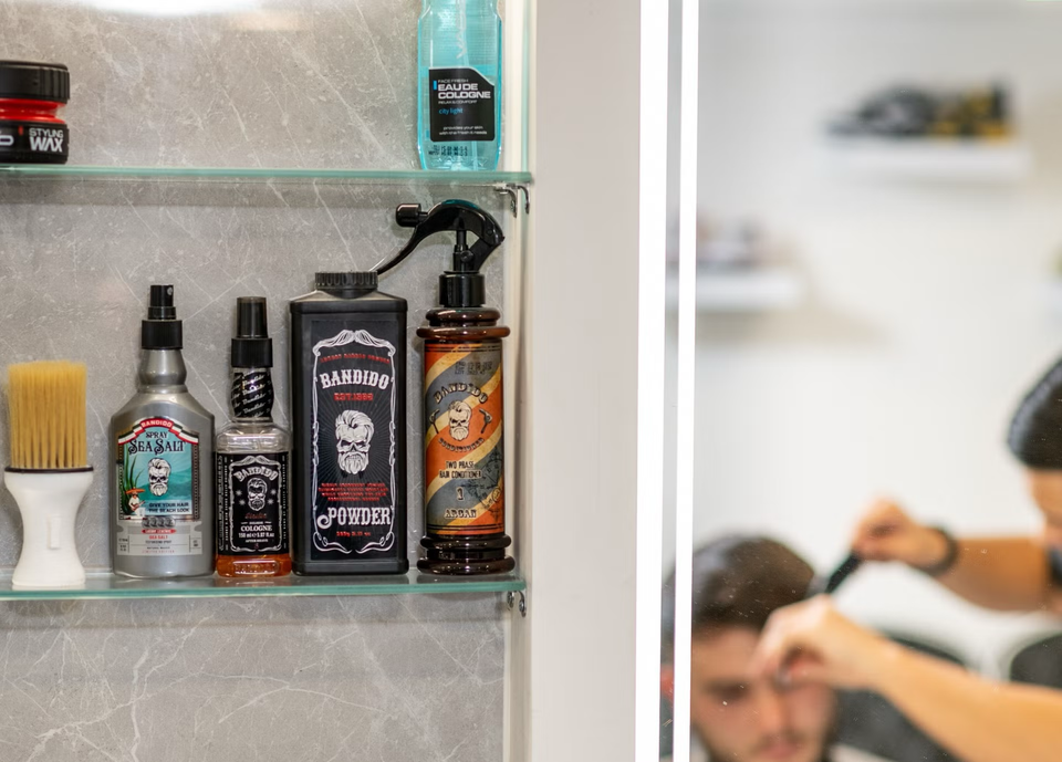 Grooming products beside a barber working in the mirror